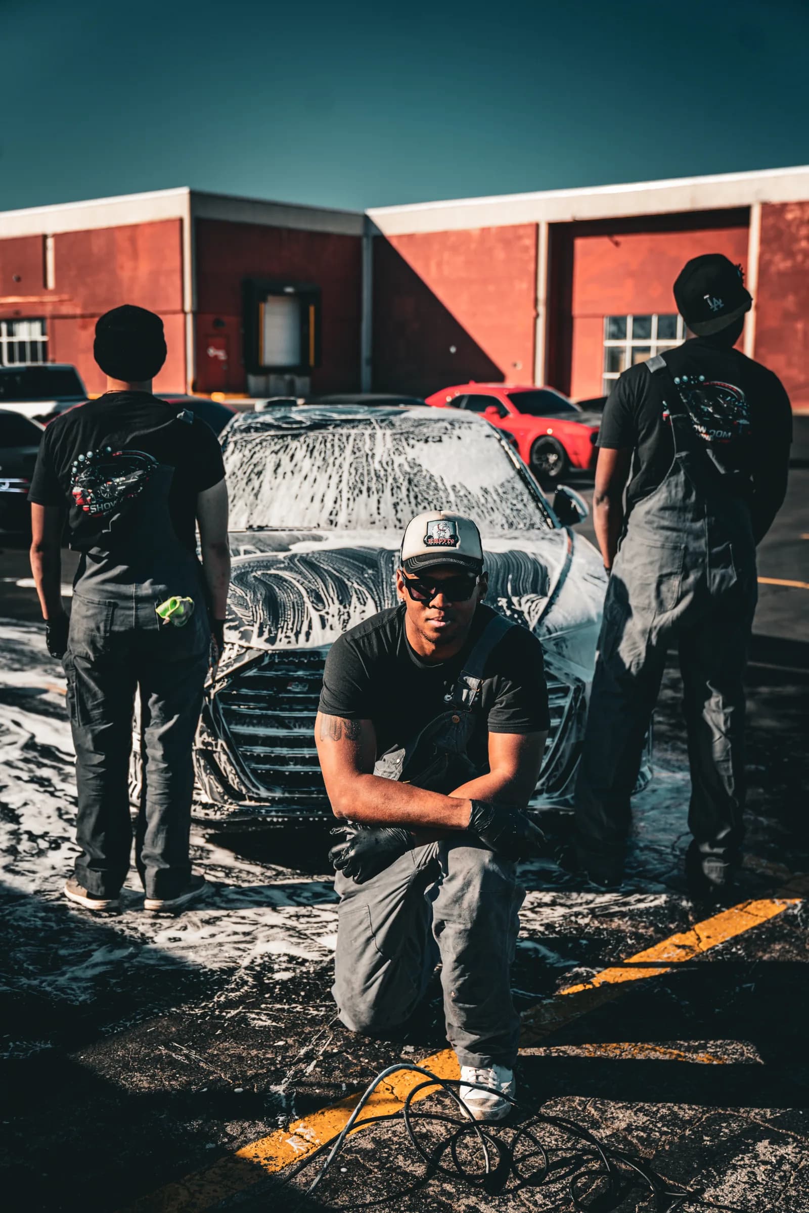 The Showroom Shine crew alongside a foam-covered car outside their shop