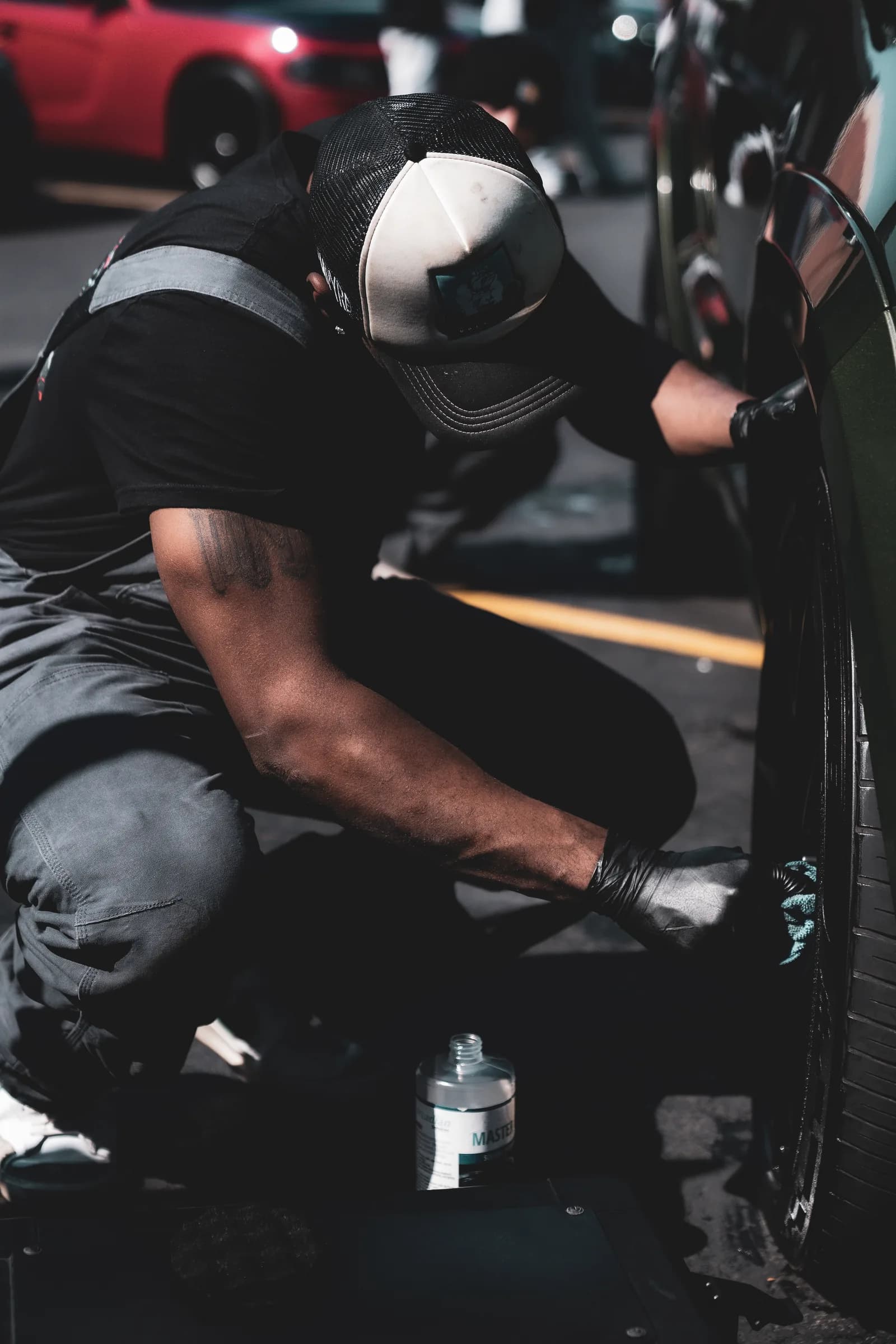 Close-up of a Showroom Shine detailer hand-cleaning a wheel and lower panel